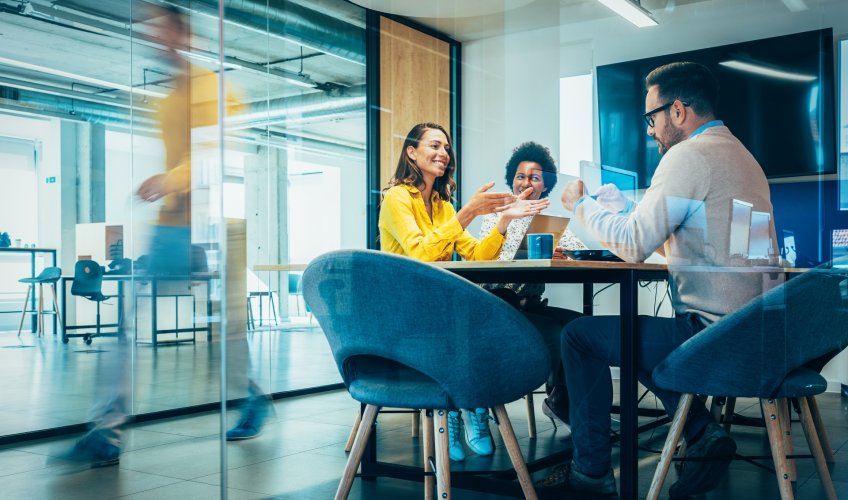 Three individuals at a table meeting. Three individuals at a table meeting.